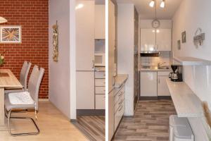 a kitchen with white cabinets and a table and chairs at Terrassenhaus, FeWo 19 in Duhnen
