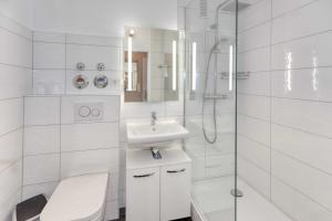 a white bathroom with a sink and a shower at Terrassenhaus, FeWo 19 in Duhnen +9 photos