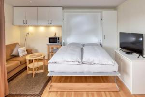 um pequeno quarto com uma cama e um sofá em Terrassenhaus, FeWo 67 em Duhnen