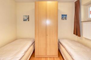 Duas camas num quarto com um armário de madeira em Terrassenhaus, FeWo 67 em Duhnen