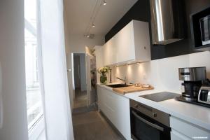 een keuken met witte kasten en een aanrechtblad bij L'Appartement : location les merciers. in La Rochelle