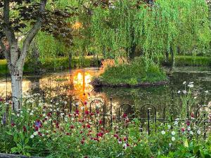 a pond in a park with flowers and trees at Rumbolds Retreat in Plaistow