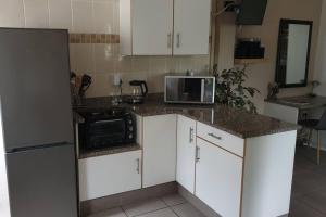 a kitchen with white cabinets and a microwave and a refrigerator at Acacia's Rest in Port Shepstone