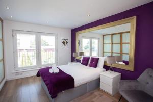 um quarto com uma cama grande e paredes roxas em Mosspark Boulevard Exec Apartment ii - Free Parking em Glasgow