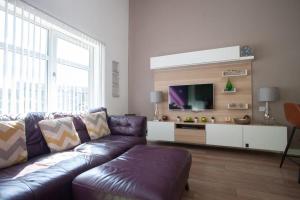 a living room with a purple couch and a tv at Mosspark Boulevard Exec Apartment ii - Free Parking in Glasgow