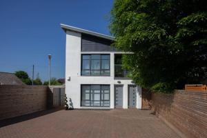 uma casa branca com janelas grandes e uma cerca de tijolos em Mosspark Boulevard Exec Apartment ii - Free Parking em Glasgow
