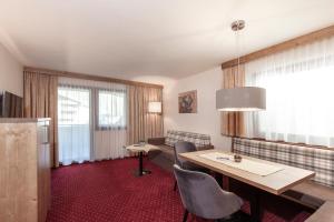 a hotel room with a table and chairs and a couch at Panorama Appartements in Längenfeld