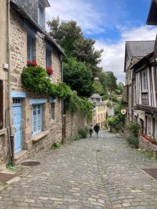 dwoje ludzi idzie po brukowanej ulicy z budynkami w obiekcie Breton stone cottage with a garden near the river w mieście La Vicomté-sur-Rance