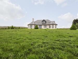 une maison blanche dans un champ d'herbe verte dans l'établissement Challenger Lodge, à Lairg