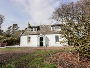 a white house with a black door in a yard at Saltflats Cottage - Rockcliffe in Dalbeattie