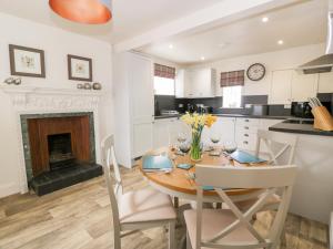 a kitchen and dining room with a table and a fireplace at Saltflats Cottage - Rockcliffe in Dalbeattie