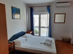 um quarto com uma cama e uma grande janela em Apartmani Baška Voda em Baska Voda