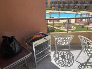 a balcony with a table and chairs and a pool at Sun Mirror Chalet El Sokhna in Ain Sokhna