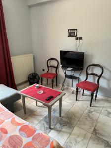 een woonkamer met 2 stoelen, een tafel en een tv bij Modern house next to Metro station to explore Athens in Athene