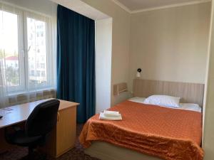 1 dormitorio con cama, escritorio y ventana en Silk Road Lodge, en Bishkek