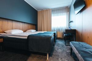 a bedroom with two beds and a desk and a window at Go Hotel Shnelli in Tallinn