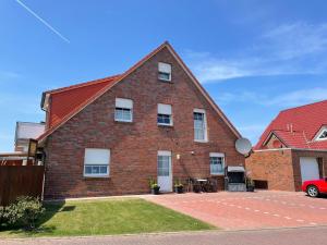 a brick house with a red roof at Windlicht im 1 Stockwerk in Norddeich
