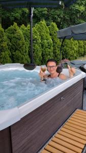 a man in a hot tub with a glass of wine at Pokoje Gościnne Ontario Mieroszyno in Jastrzębia Góra