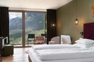a bedroom with a bed and a view of a mountain at Oliven- & Genusshotel Hirzer in Schenna