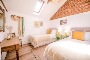 a bedroom with two beds and a table and a window at The Stables, Hoo in Woodbridge