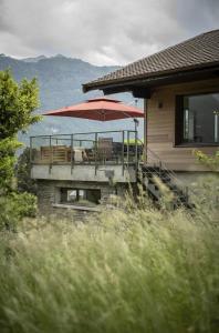 Casa con terraza con sombrilla roja en Venez Chez Vous - Chalet de Bredanne - Bord du lac, en Doussard