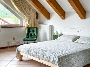 a bedroom with a bed and a green chair at Le Mansarde di Siberia in Craveggia