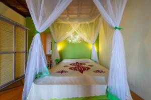 un dormitorio con una cama con dosel en La Plage de Le Zahir, en Nosy Be