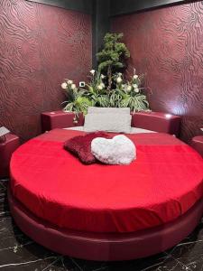 Una cama roja con una almohada en forma de corazón. en DEVILTHON SUITE NETTUNO, en Nettuno
