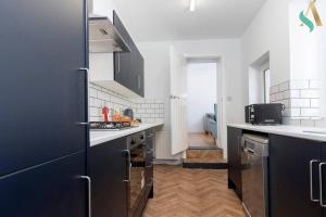 uma cozinha com armários pretos e um frigorífico azul em Thornaby Road TSAC em Stockton-on-Tees