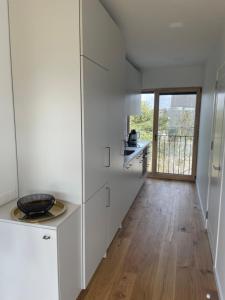 a kitchen with white cabinets and a wooden floor at Vėtrungės apartamentai III in Svenele