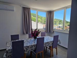 a dining room with a table and chairs and windows at Mia Podgora in Podgora