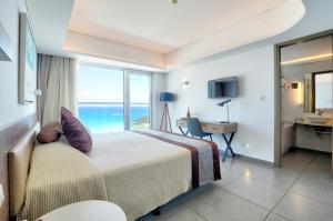 a bedroom with a bed with a view of the ocean at Vassos Nissi Plage Hotel & Spa in Ayia Napa