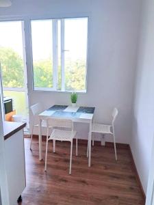 una mesa blanca y sillas en una habitación con ventanas en Lidda Apartment in residential area en Varna