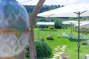 Cantine Cipri Resort في بالمي: حديقة فيها مظلات بيضاء وطاولات وكراسي