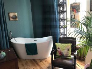 a bath tub in a room with a chair at La maison bleue in Pont-Aven