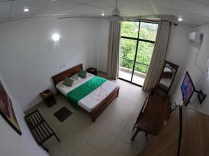 um quarto com uma cama e uma grande janela em Ambalama Leisure Lounge em Hanwella