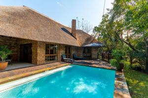 an outdoor swimming pool in front of a thatched house at Kruger Park Lodge Unit No 252 with private pool in Hazyview