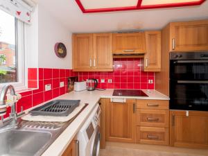a kitchen with wooden cabinets and red tile at Pass the Keys Cosy Flat close to Train Station and Centre in Reading