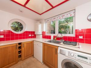 a red tiled kitchen with a sink and a washing machine at Pass the Keys Cosy Flat close to Train Station and Centre in Reading