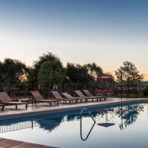 a swimming pool with lounge chairs next to a fence at Cabañas El Refugio del Mensu in Puerto Iguazú