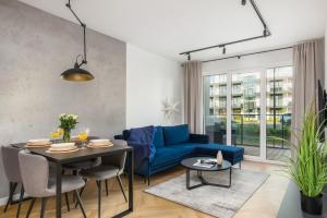 a living room with a blue couch and a table at Wellness & SPA Resort Dziwnów Apartments with Parking by Renters Prestige in Dziwnów