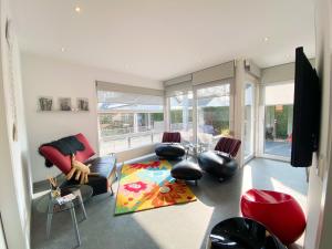 Una sala de estar con un sofá, sillas y ventanas. en Vakantiehuis Zee, Bos & Duin Zoutelande ZO01, en Zoutelande
