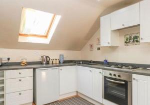 uma cozinha com armários brancos e uma janela em Willow cottage with private hot tub em Upper Hulme