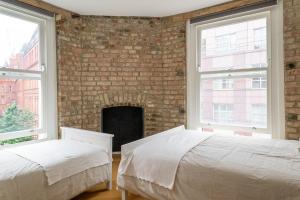twee bedden in een kamer met een bakstenen muur bij City Air Apartments - HATTON GARDEN - GREAT TRANSPORT LINKS in Londen