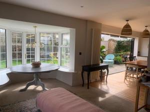 a living room with a table and some windows at Cedar Shade Cottage in Sidmouth