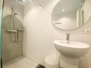 Un baño blanco con lavabo y espejo. en Vakantiehuis Zee, Bos & Duin Zoutelande ZO01, en Zoutelande 18 fotos más