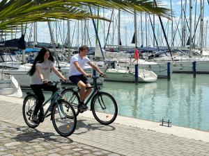 Un homme et une femme à bord de vélos près d'un port de plaisance dans l'établissement Hotel Marina Port, à Balatonkenese
