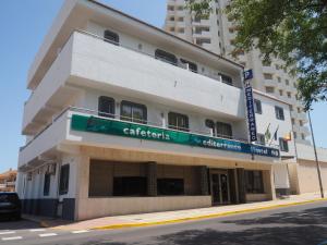 a large white building with a green sign on it at Hostal Mediterraneo in El Ejido