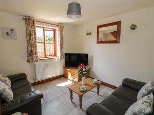 a living room with a couch and a tv at Avoine Cottage in Gloucester