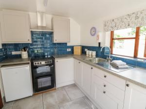 a kitchen with white cabinets and a stove top oven at Avoine Cottage in Gloucester